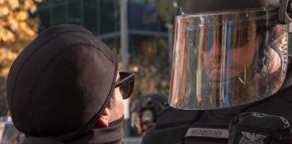 protester faces police officer in riot gear
