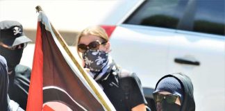 Masked protesters holding a black and red flag