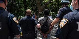 Police escort a handcuffed man across a city street