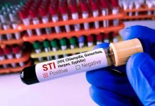 Controversial AIDS-Era Ban Brought Back! Gloved hand holding an STI test tube labeled positive