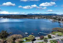 Aerial view of a lakeside town with pier and boats under a blue sky