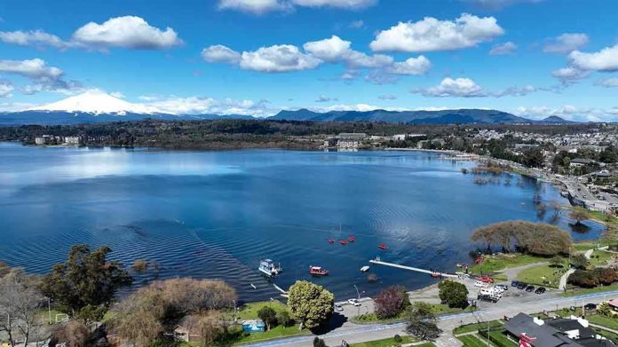 Aerial view of a lakeside town with pier and boats under a blue sky
