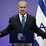 ICC Warrant Shadows Netanyahu’s UN Gamble man in suit speaking at a podium with Israeli flag