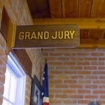 Juror Held in Safehouse- ATTACKED For Being Republican Grand jury sign in a brick-walled hallway