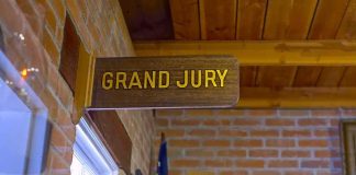 Juror Held in Safehouse- ATTACKED For Being Republican Grand jury sign in a brick-walled hallway