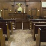 Interior view of an empty courtroom with wooden benches and a judges bench
