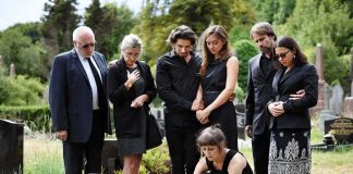 Mourners gathered at a graveside placing flowers