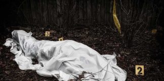 covered body at outdoor crime scene with evidence markers
