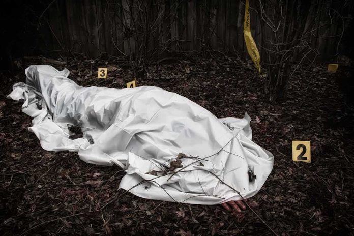 covered body at outdoor crime scene with evidence markers