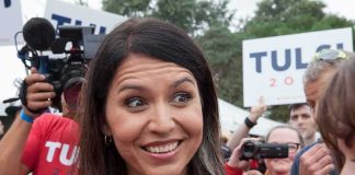 Tulsi Gabbard smiling at an outdoor event surrounded by supporters