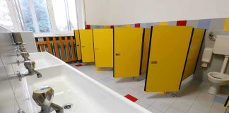School bathroom with yellow stall doors and long sink