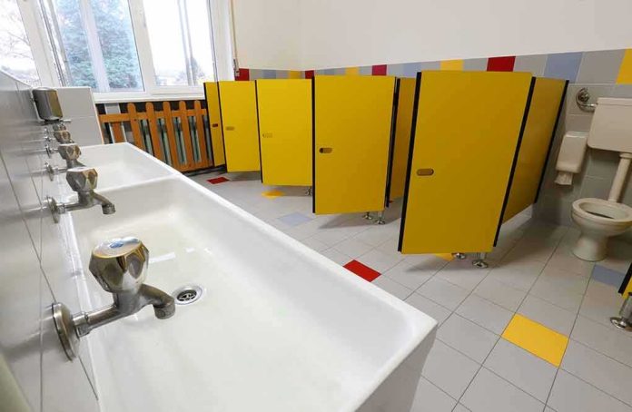 School bathroom with yellow stall doors and long sink