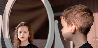 boy looking at reflection of a girl in an oval mirror