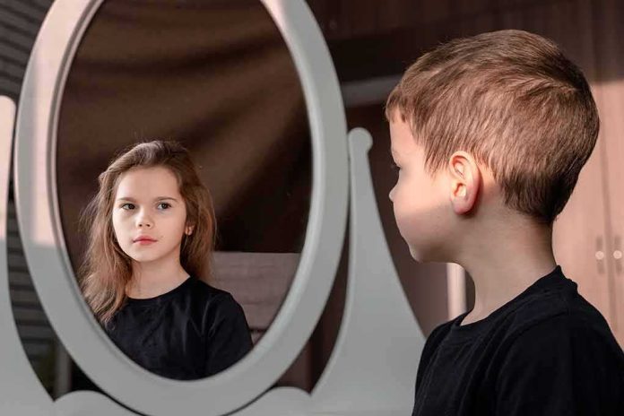 boy looking at reflection of a girl in an oval mirror