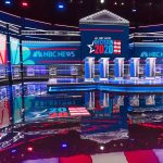 Dem Darling ROCKED By Another Harassment Scandal Televised debate stage with multiple podiums and bright red, white, and blue lighting