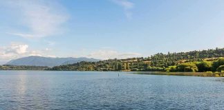 Calm lake with forested hills under a clear blue sky