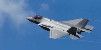 Stealth fighter jet banking in a clear blue sky