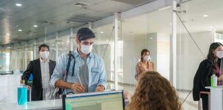 Passengers wearing masks check in at an airport counter