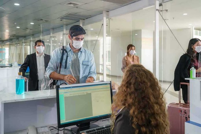 Passengers wearing masks check in at an airport counter