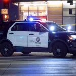 ICE Shooting Sparks Fury – City Riots ERUPT Police SUV blocks an intersection at night with lights flashing