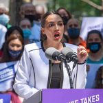 Ghetto Rep Goes On Racist Rant – “We Owe Black Women!” Woman speaking at outdoor podium with microphones