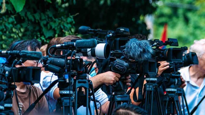 shutterstock_2210577723-6 TV news cameras crowding together at an outdoor event