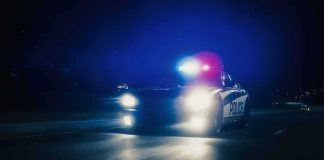 Police car with flashing lights driving at night