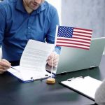 Veterans Panic Rising – VA Turns Its Back Two people at a desk reviewing documents with a small American flag by a laptop