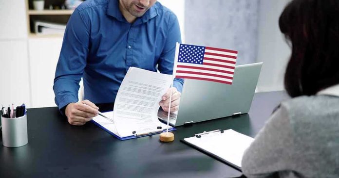 Two people at a desk reviewing documents with a small American flag by a laptop
