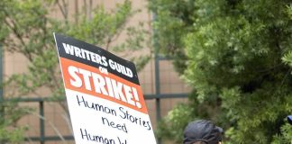 Protesters holding a strike sign at an outdoor rally