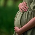Pregnant woman holding her belly in a green dress
