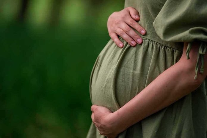 Pregnant woman holding her belly in a green dress
