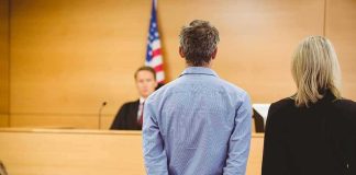 Defendant in handcuffs standing before a judge in a courtroom