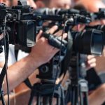Gay Group Drops Trans Support television cameras on tripods at a media event