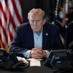 Trump Takes WRECKING Ball To JFK Memorial Person in suit seated at table with telephones
