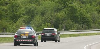 Police car with flashing lights following a minivan on a highway