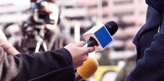 Reporters hold microphones during an outdoor interview
