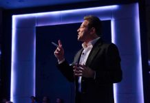 Man in suit giving a presentation on stage with blue backlighting