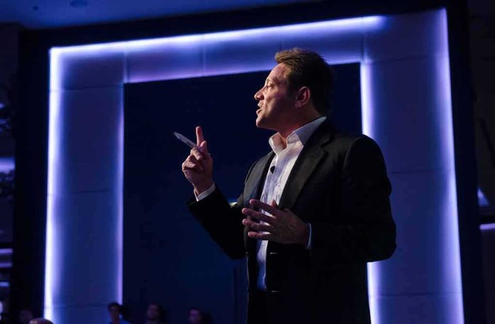shutterstock_746943895 Man in suit giving a presentation on stage with blue backlighting