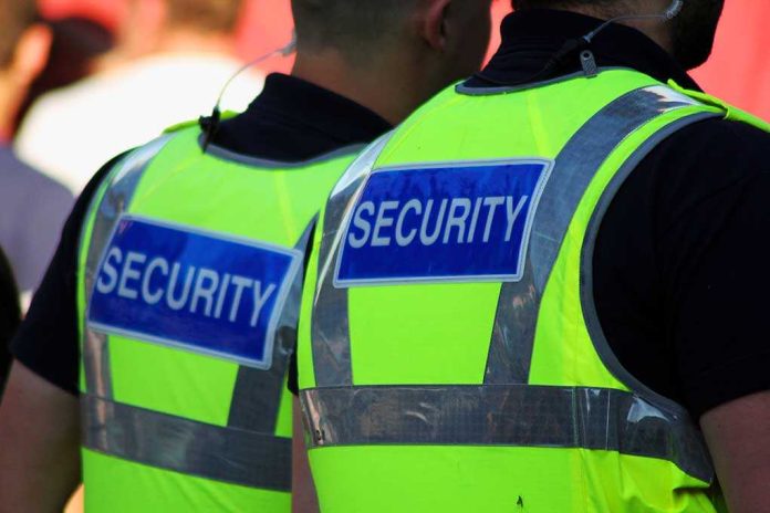 shutterstock_76002502 Two security personnel wearing high visibility vests with SECURITY printed on the back