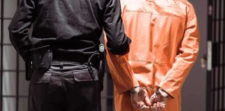 Trump to Execute Paraplegic Palestinian Prisoner in orange jumpsuit handcuffed with guard standing beside