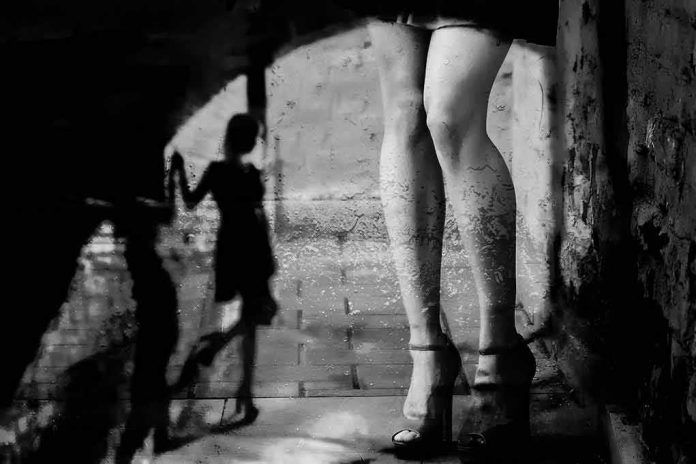 legs in high heels under an archway with blurred shadow figure