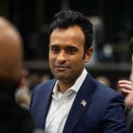 Ramaswamy Roasted For Ridiculous Child Stunt During Trump Rally man in a navy suit with a flag pin speaking with people