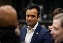 Ramaswamy Roasted For Ridiculous Child Stunt During Trump Rally man in a navy suit with a flag pin speaking with people