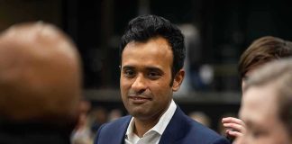 Ramaswamy Roasted For Ridiculous Child Stunt During Trump Rally man in a navy suit with a flag pin speaking with people