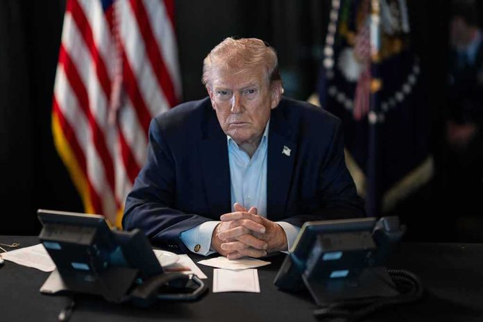 shutterstock_2747572821-1 Donald Trump seated at a table between two desk phones